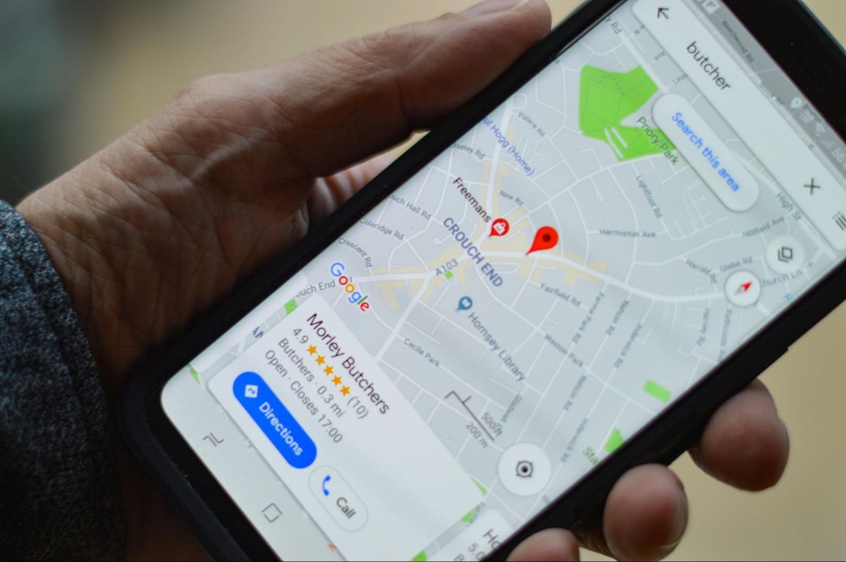 Hand holding a phone with Google Maps search results for a local shop