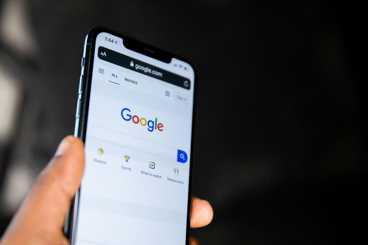 Hand holding a phone open to the Google search page in low light