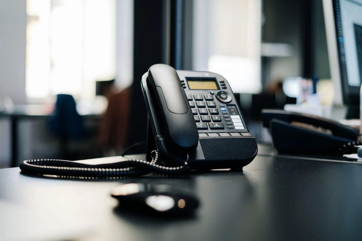 Black office desk phone with a coiled cord