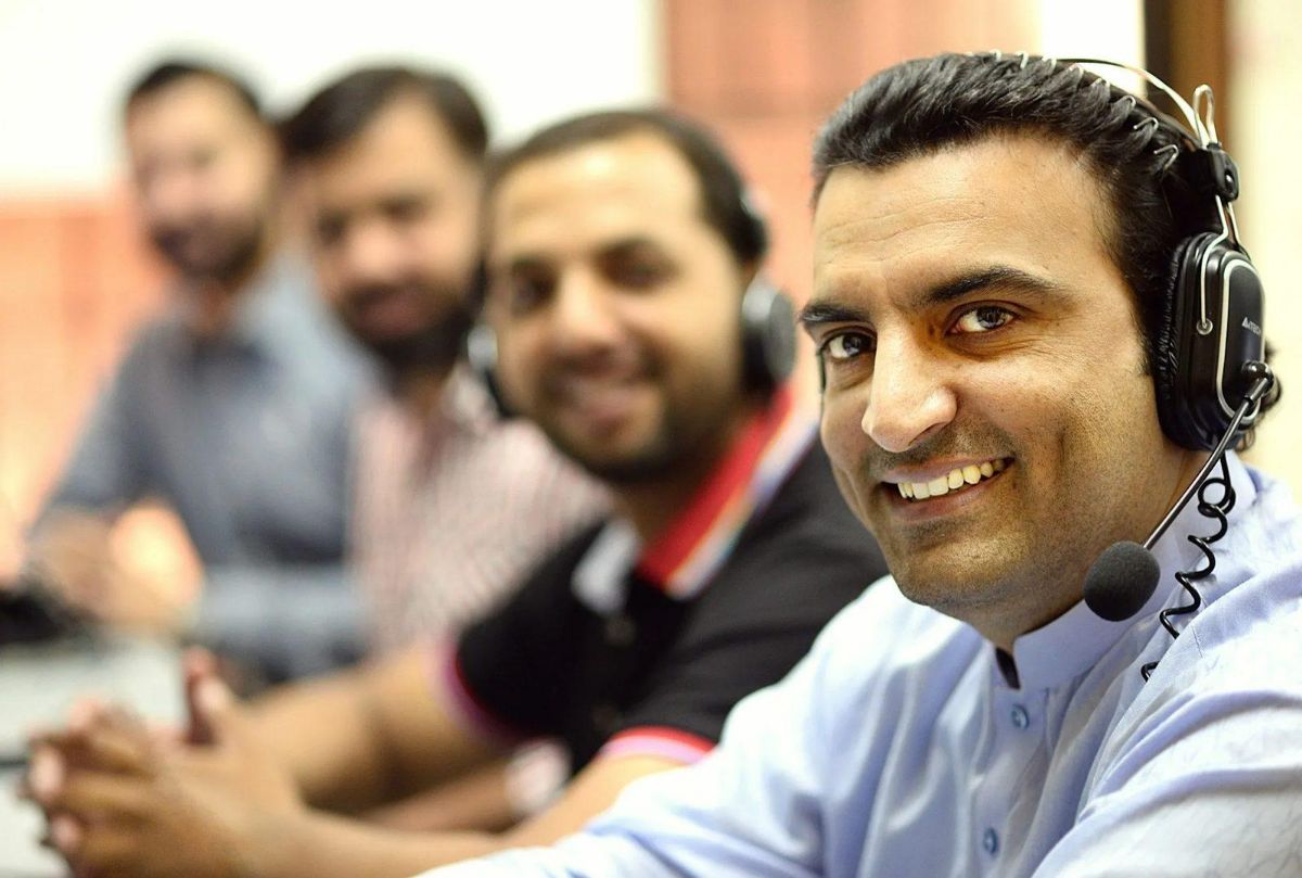 Smiling man wearing a phone headset at a call center desk