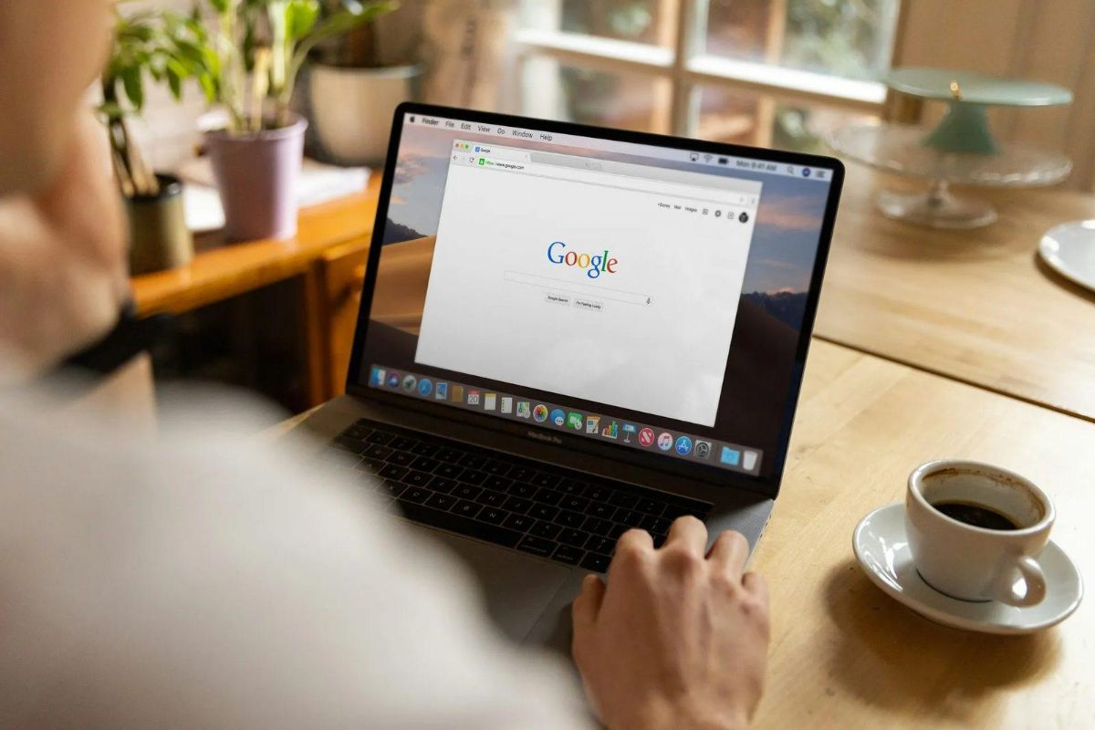 Laptop showing the Google search homepage next to a cup of espresso