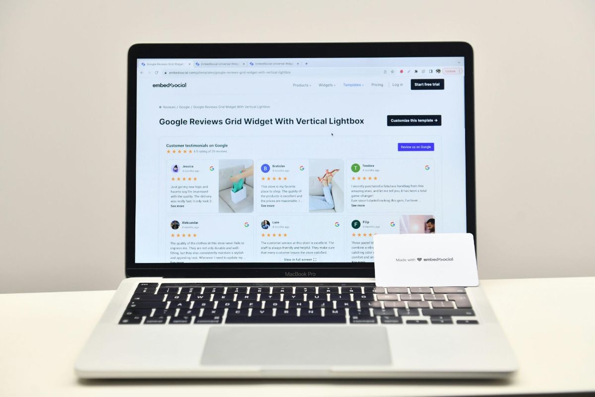 Laptop on a white desk showing a grid of Google reviews on a web page