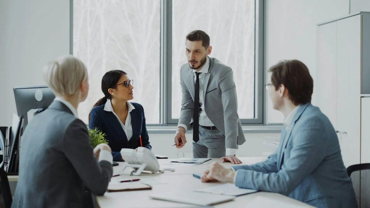 Four coworkers talking around a white conference table