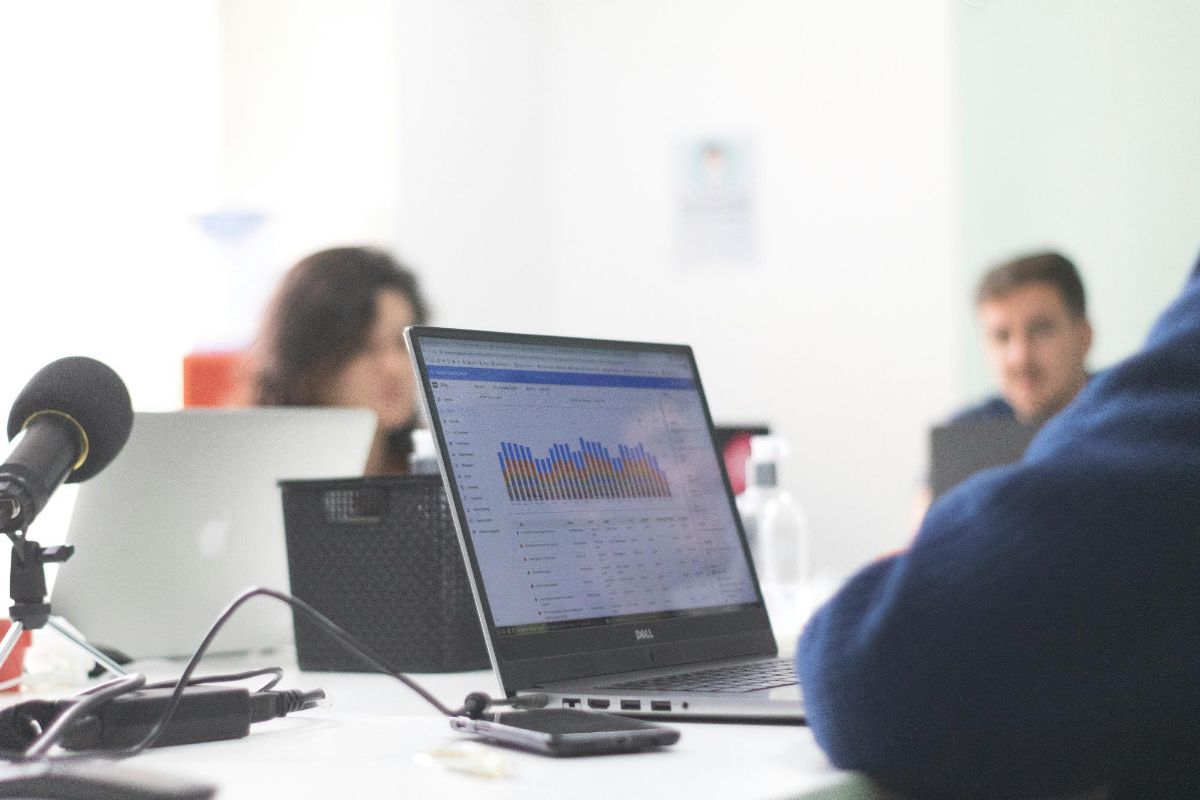 Laptop showing colorful bar charts on an office desk during a meeting