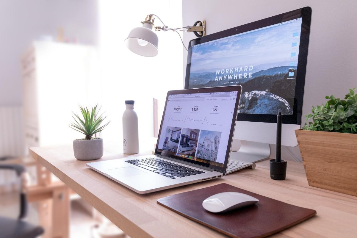 Wooden desk with a laptop, a second monitor, a lamp and a plant