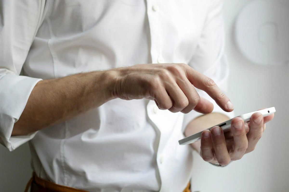 Man in a white shirt tapping on a smartphone screen
