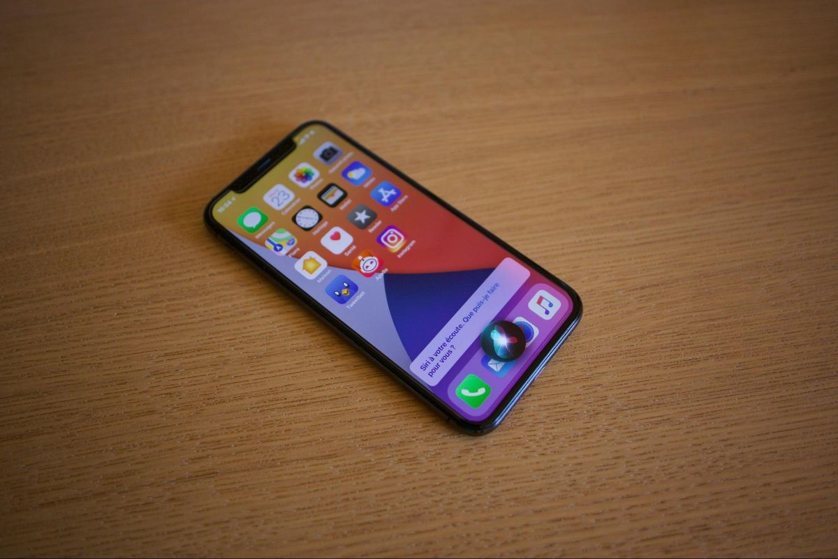 Phone lying on a wooden table with Siri open over the home screen